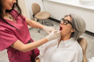A smiling, diverse group of patients are in a modern dental office waiting room, with a friendly receptionist in the background. No text on image.